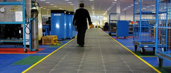Homem caminhando por uma fábrica em que o ambiente está limpo e organizado, dessa forma estimula o engajamento dos colaboradores.